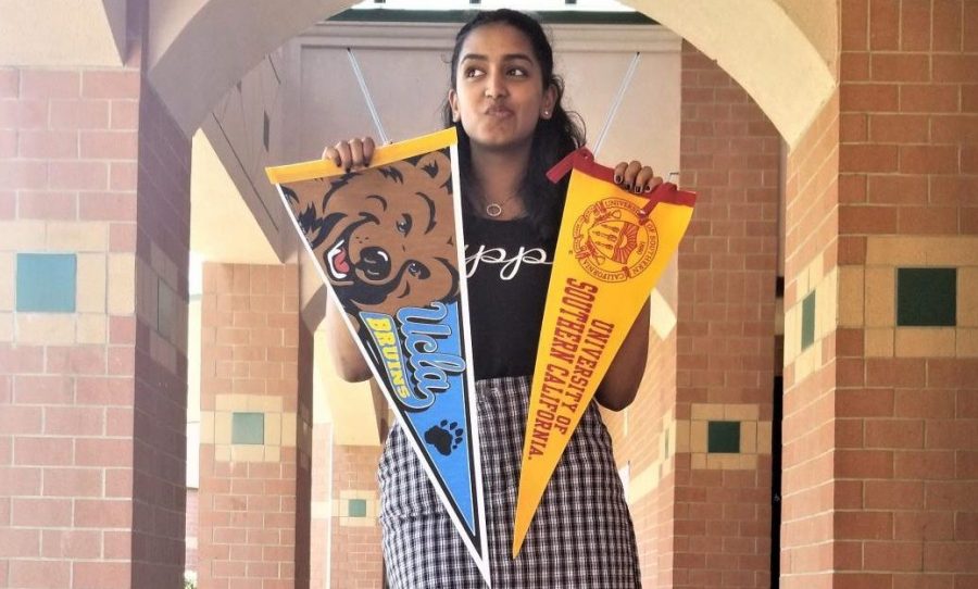 GBHS graduate Manvi Bhapkar holds up two college banners and deliberates about the different college she was considering for her freshman year of college. 