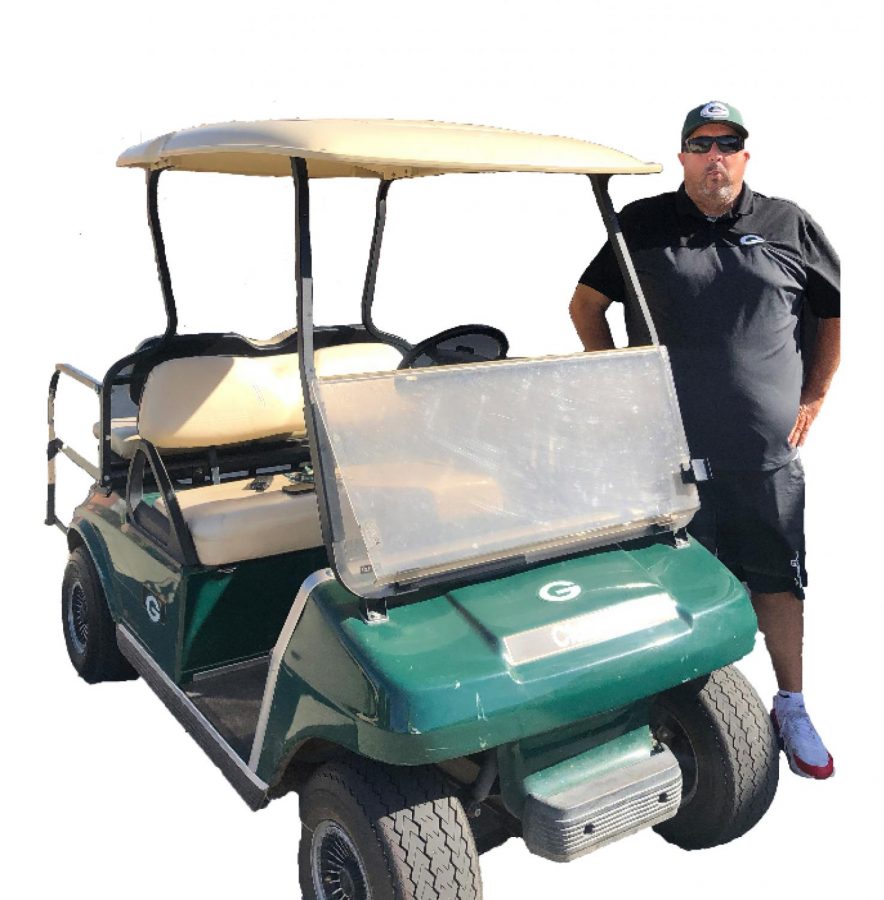 Campus monitor, Jason Ott, poses next to his infamous golf cart.