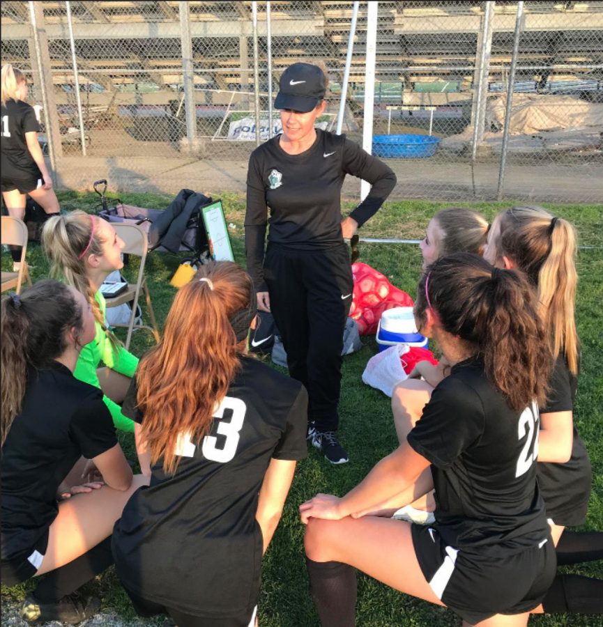 Varsity girls soccer players take a knee at one of their last games with their coach, Katy Vivaldi.