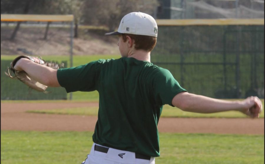 Varsity+baseball+player+Derek+Schwarze+rounds+up+to+practice+his+throw+on+the+field.+