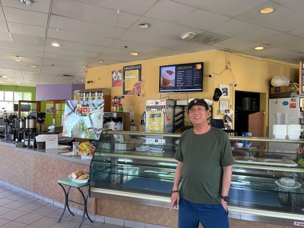 Quang Tran, the owner of La Bou, smiles in front of the display of baked goods.