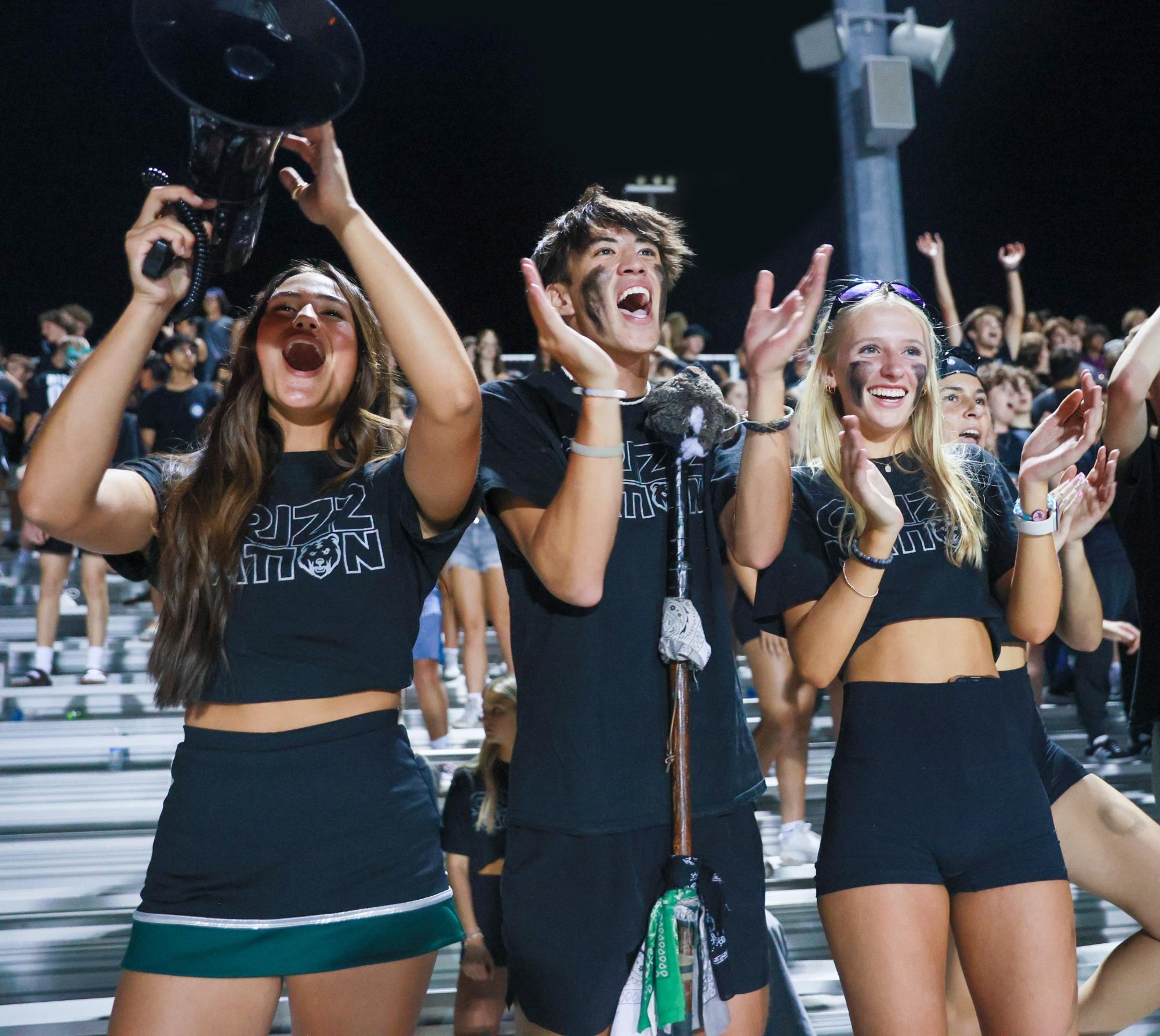 Grizz Nation Leaders Maile Zeng and Niko Bannai cheer alongside senior Reese Gotchall 